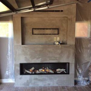 Grey stone gas fireplace with TV mount space above it - plastic on the sides and long gas fireplace on the bottom.