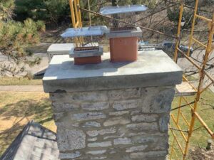 Restored stone chimney masonry, newly poured Concrete Crown and new stainless steel Chimney Caps After rebuild