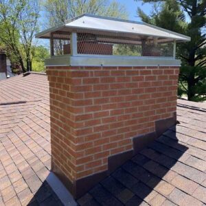 Red brick masonry chimney with custom-fitted double flue stainless steel chimney cap