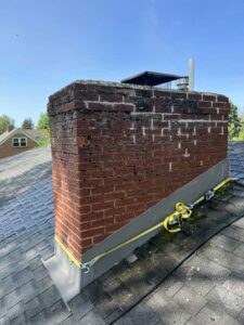 Brick chimney with damaged and crumbling masonry and crown before rebuild